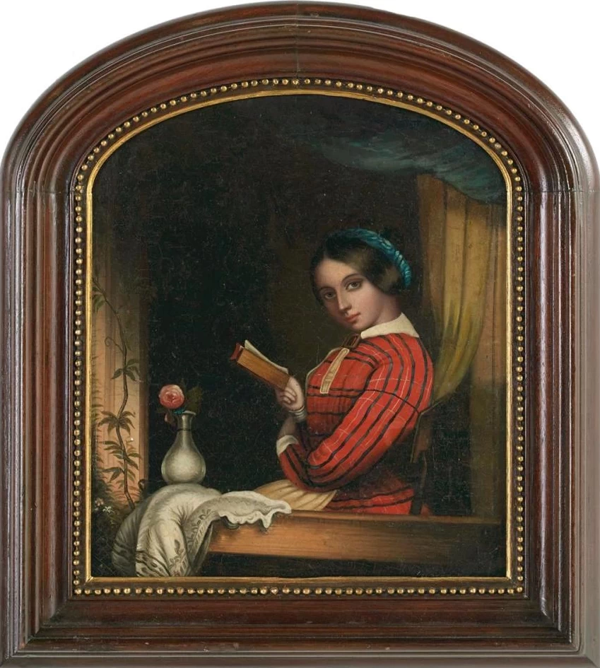 Giovane donna che legge accanto alla finestra